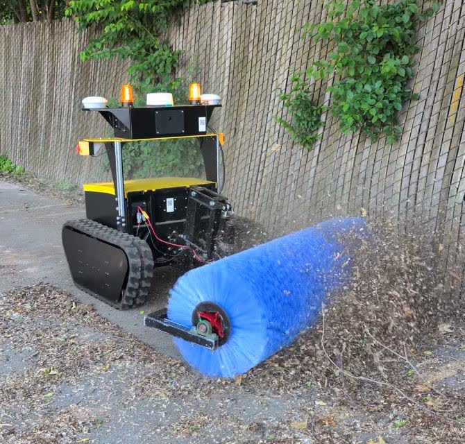 Snowbotix sweeping robot cleaning a parking lot surface with its debris collection system